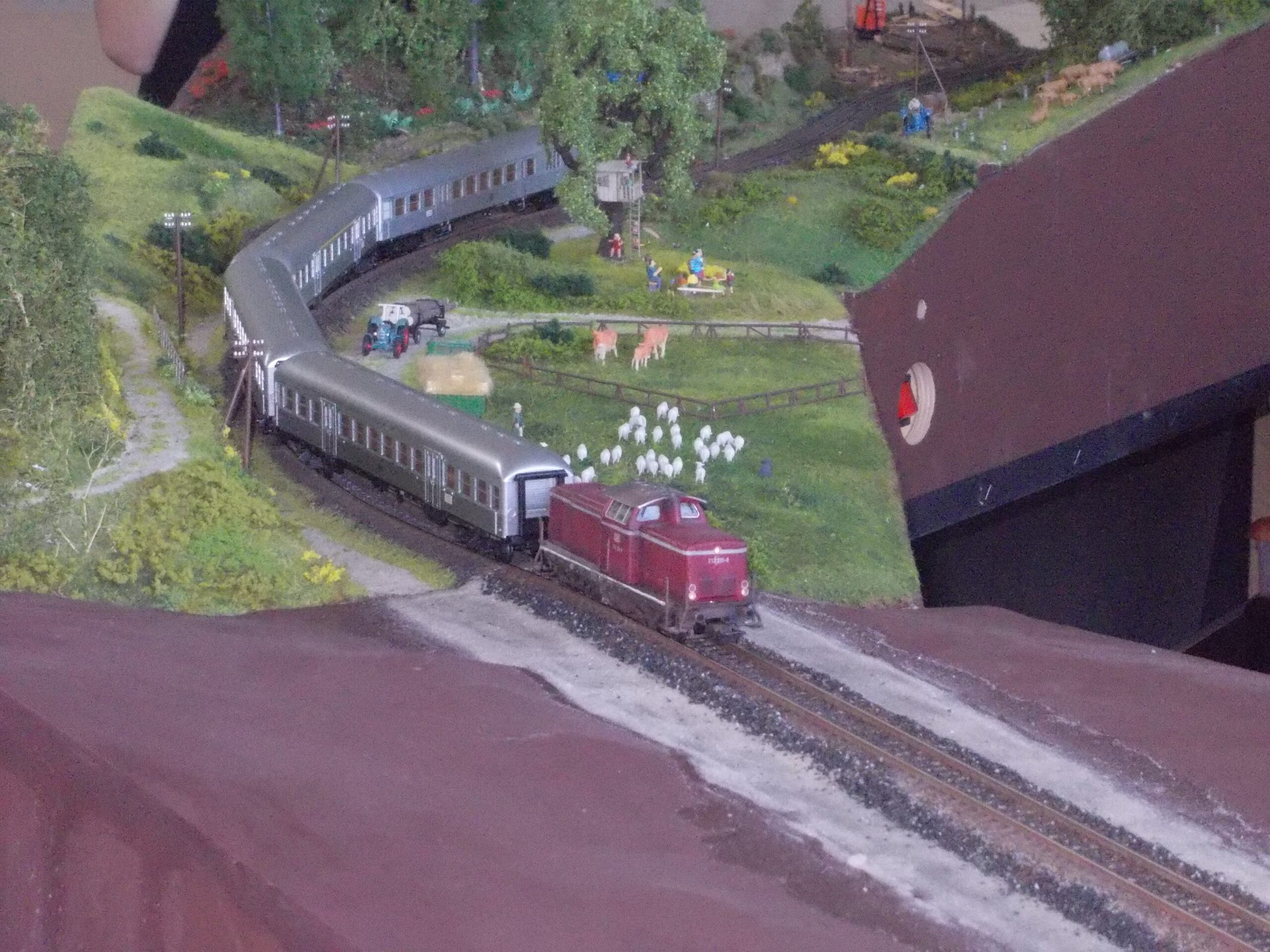 Modelleisenbahnanlage mit detaillierter Miniaturlandschaft, Zügen, Bäumen und Tierfiguren