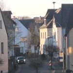 Blick durch eine enge Dorfstraße mit traditionellen Steinhäusern bei Dämmerung oder frühem Morgen