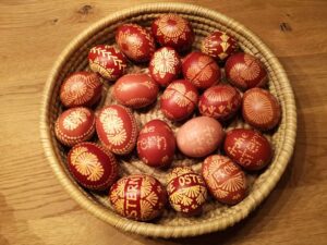 Korb mit kunstvoll dekorierten Ostereiern in Rottönen mit gelben Mustern und Schriftzügen "Frohe Ostern" in sorbischer Tradition